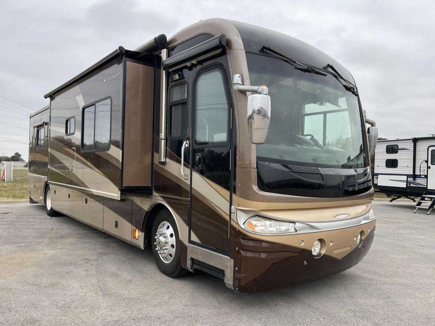 2006 FLEETWOOD REVOLUTION 40J (4VZBR1J9X6C) , Length: 40 ft | GVWR: 34,000 lbs | Slides: 3 transmission, located at 4319 N Main Street, Cleburne, TX, 76033, (817) 221-0660, 32.435829, -97.384178 - The 2006 Fleetwood Revolution 40E is a stylish and well-maintained travel trailer. It has 77,049 miles on it! The front has a sleek and rounded windshield that offers excellent visibility for the driver. Its two-tone color scheme of brown, beige, and gold gives it a luxurious look. The chrome side m - Photo#0