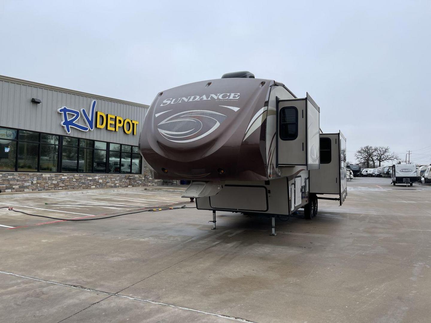 2014 TAN SUNDANCE 2880RLT (5SFSG3320EE) , Length: 32.2 ft. | Dry Weight: 9,750 lbs. | Gross Weight: 13,800 lbs. | Slides: 3 transmission, located at 4319 N Main Street, Cleburne, TX, 76033, (817) 221-0660, 32.435829, -97.384178 - This 2014 Sundance Fifth Wheel is just over 32 feet long and 8 feet wide. It has a GVWR of 13,800 lbs and a hitch weight of 2,220 lbs. The exterior of this fifth wheel is a stylish grey with brown, white, and beige decals. This model also has three slides and a 16-foot power-retractable awning. The - Photo#0