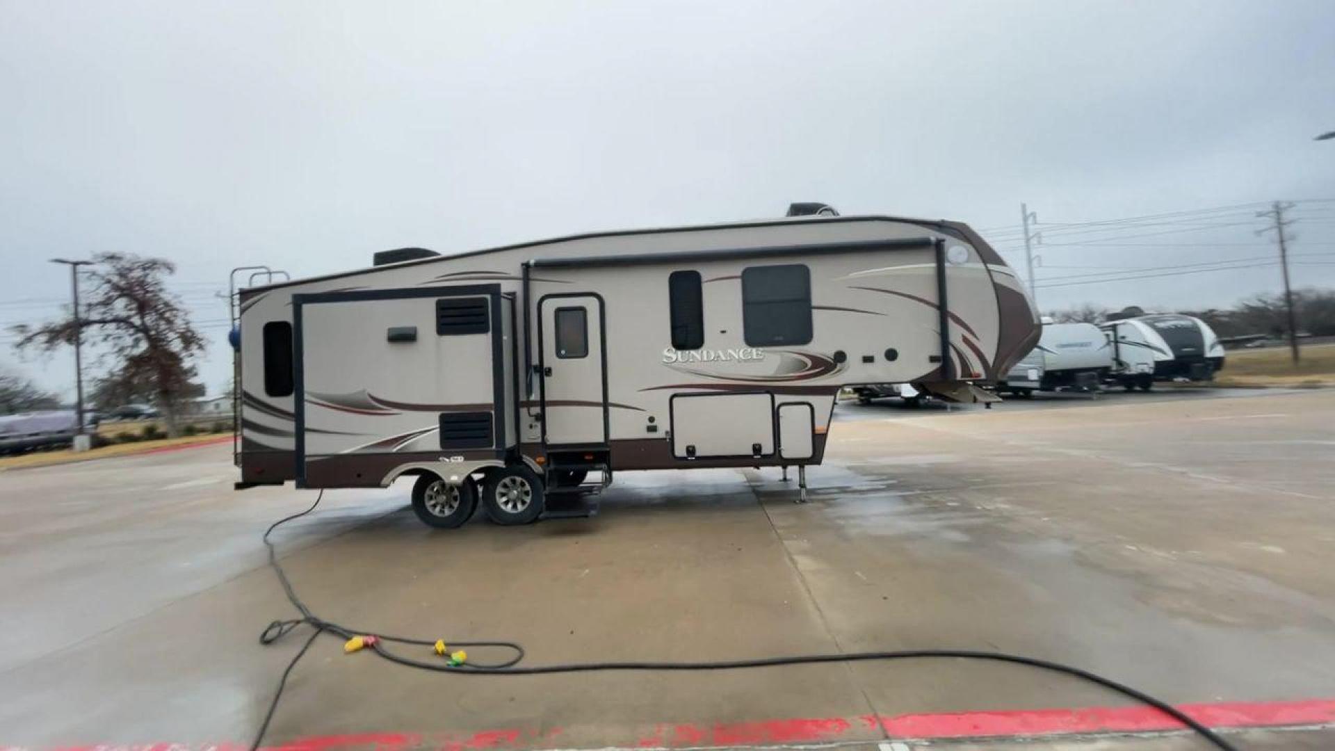 2014 TAN SUNDANCE 2880RLT (5SFSG3320EE) , Length: 32.2 ft. | Dry Weight: 9,750 lbs. | Gross Weight: 13,800 lbs. | Slides: 3 transmission, located at 4319 N Main Street, Cleburne, TX, 76033, (817) 221-0660, 32.435829, -97.384178 - This 2014 Sundance Fifth Wheel is just over 32 feet long and 8 feet wide. It has a GVWR of 13,800 lbs and a hitch weight of 2,220 lbs. The exterior of this fifth wheel is a stylish grey with brown, white, and beige decals. This model also has three slides and a 16-foot power-retractable awning. The - Photo#2