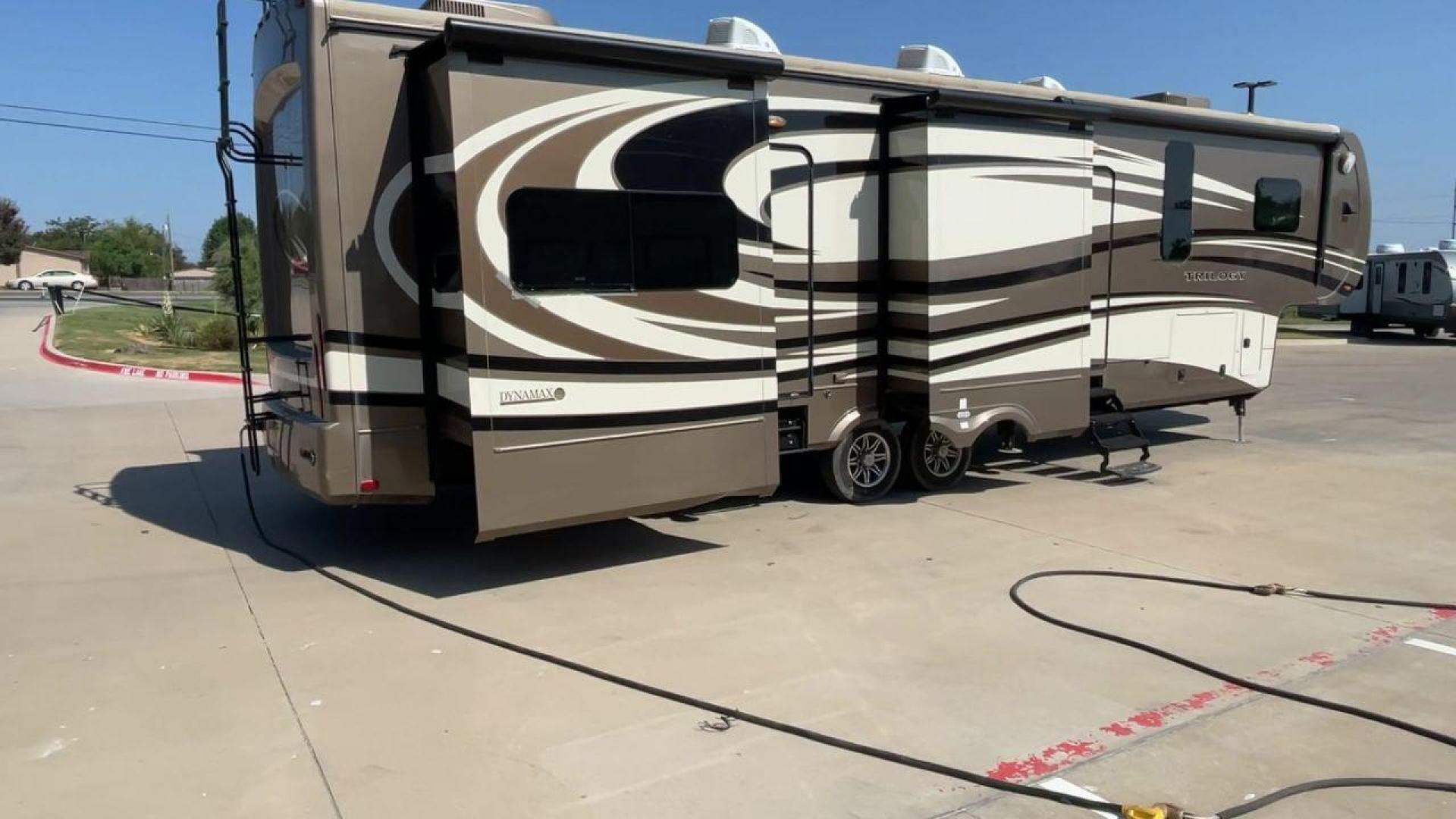 2015 TAN DYNAMAX TRILOGY 37BH - (5ZT3TL2B8FC) , Length: 42 ft. | Dry Weight: 15,638 lbs. | Gross Weight: 18,550 lbs. | Slides: 5 transmission, located at 4319 N Main Street, Cleburne, TX, 76033, (817) 221-0660, 32.435829, -97.384178 - This 2015 Trilogy Dynamax 37BH fifth wheel has 42.9 ft in length, 8.4 ft in width, and 13.2 ft in height. It has a dry weight of 15,638 lbs with a GVWR of 18,550 lbs and a hitch weight of 2,550 lbs. The exterior features a front storage capacity with a generator prep. It has extra-large pass-through - Photo#1