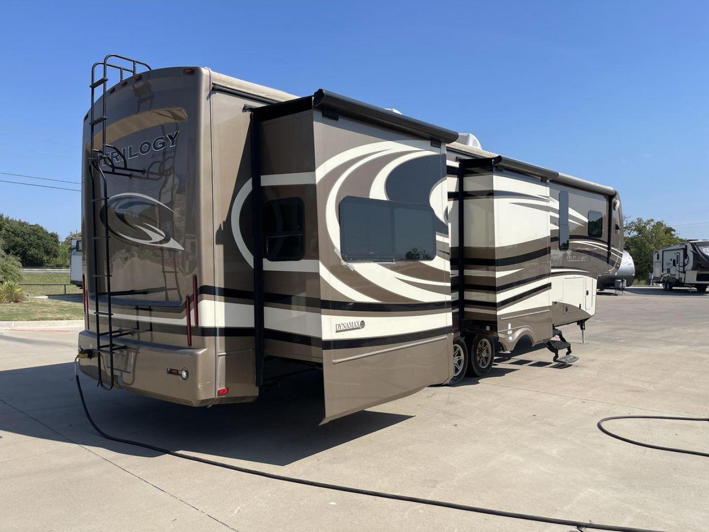 2015 TAN DYNAMAX TRILOGY 37BH - (5ZT3TL2B8FC) , Length: 42 ft. | Dry Weight: 15,638 lbs. | Gross Weight: 18,550 lbs. | Slides: 5 transmission, located at 4319 N Main Street, Cleburne, TX, 76033, (817) 221-0660, 32.435829, -97.384178 - This 2015 Trilogy Dynamax 37BH fifth wheel has 42.9 ft in length, 8.4 ft in width, and 13.2 ft in height. It has a dry weight of 15,638 lbs with a GVWR of 18,550 lbs and a hitch weight of 2,550 lbs. The exterior features a front storage capacity with a generator prep. It has extra-large pass-through - Photo#24