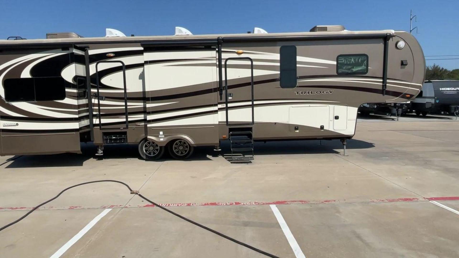 2015 TAN DYNAMAX TRILOGY 37BH - (5ZT3TL2B8FC) , Length: 42 ft. | Dry Weight: 15,638 lbs. | Gross Weight: 18,550 lbs. | Slides: 5 transmission, located at 4319 N Main Street, Cleburne, TX, 76033, (817) 221-0660, 32.435829, -97.384178 - This 2015 Trilogy Dynamax 37BH fifth wheel has 42.9 ft in length, 8.4 ft in width, and 13.2 ft in height. It has a dry weight of 15,638 lbs with a GVWR of 18,550 lbs and a hitch weight of 2,550 lbs. The exterior features a front storage capacity with a generator prep. It has extra-large pass-through - Photo#2