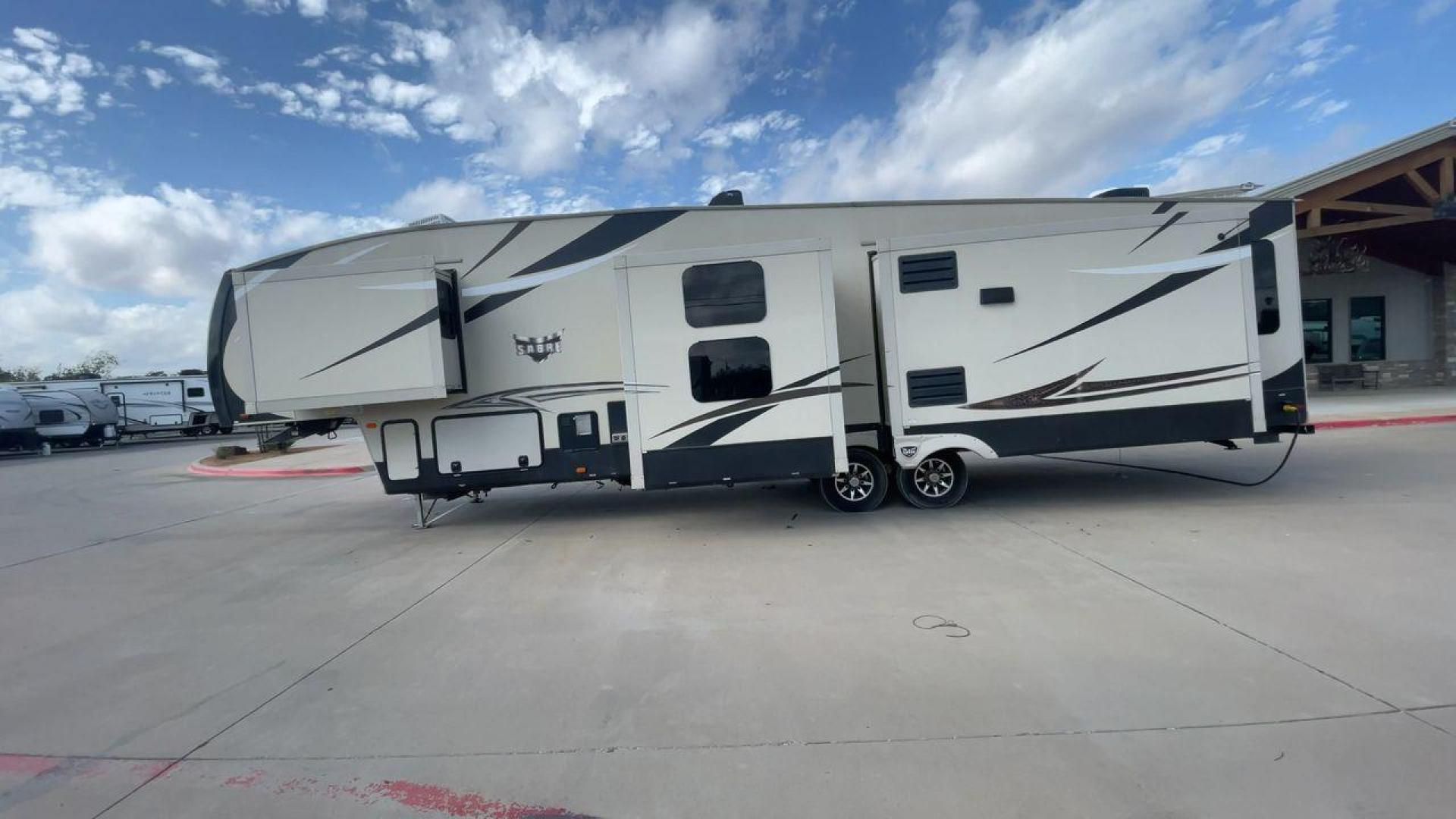 2016 TAN SABRE 365MB (4X4FSRN29G3) , Length: 42.42 ft. | Dry Weight: 12,994 lbs. | Gross Weight: 15,500 lbs. | Slides: 4 transmission, located at 4319 N Main Street, Cleburne, TX, 76033, (817) 221-0660, 32.435829, -97.384178 - The 2016 Sabre 365MB Fifth Wheel stretches 42.42 feet in length, with a commanding presence on the road and at the campground. The exterior is finished in a beige and black color scheme, accented with bold swooping graphics that add an athletic flair to its overall look. The side profile features fo - Photo#6