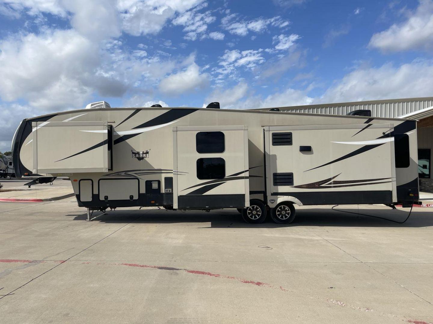 2016 TAN SABRE 365MB (4X4FSRN29G3) , Length: 42.42 ft. | Dry Weight: 12,994 lbs. | Gross Weight: 15,500 lbs. | Slides: 4 transmission, located at 4319 N Main Street, Cleburne, TX, 76033, (817) 221-0660, 32.435829, -97.384178 - The 2016 Sabre 365MB Fifth Wheel stretches 42.42 feet in length, with a commanding presence on the road and at the campground. The exterior is finished in a beige and black color scheme, accented with bold swooping graphics that add an athletic flair to its overall look. The side profile features fo - Photo#23